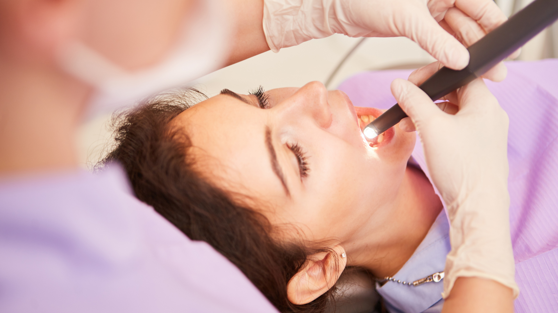 dentist looking into a patient's mouth using a dental torch.